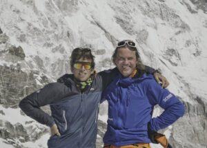 The climbers stand shoulder to shoulder with the SE face of Cho Oyu behind them.