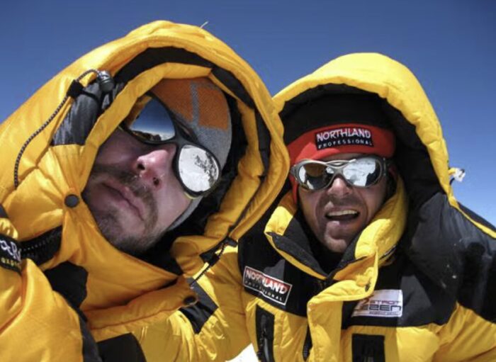 Close shot of the two climbers with high altitud clothing and sunglasses. 
