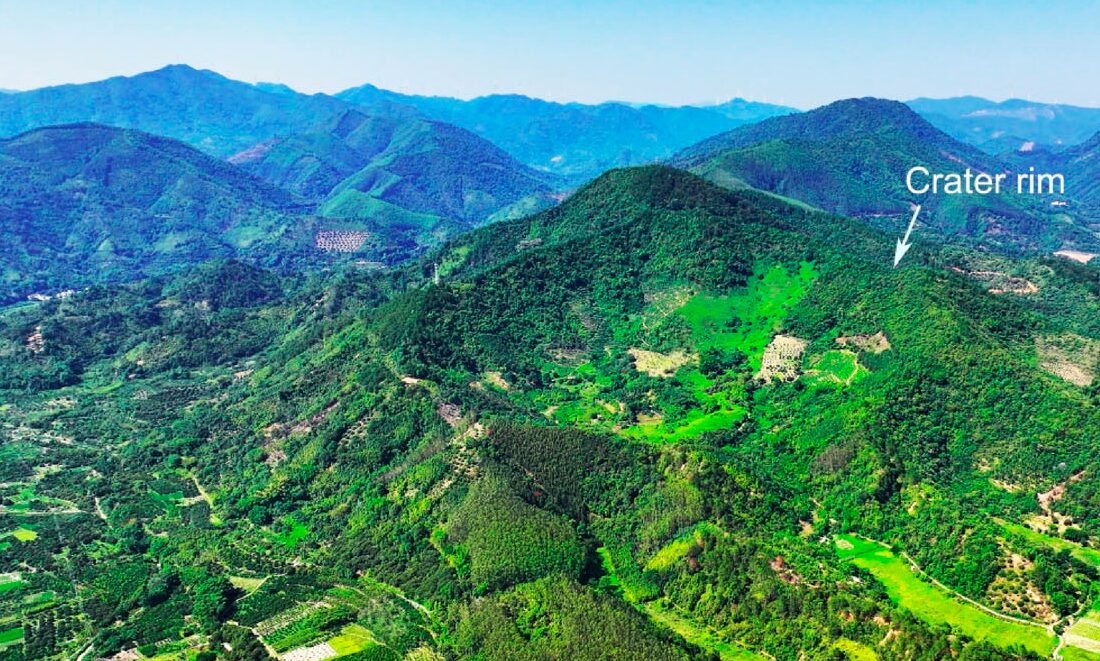aerial view of a green mountainside and visible crater