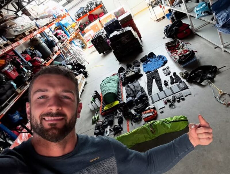 A man in front of an organized pile of kit