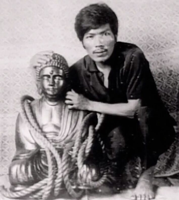 Philipino man beside small buddha statue