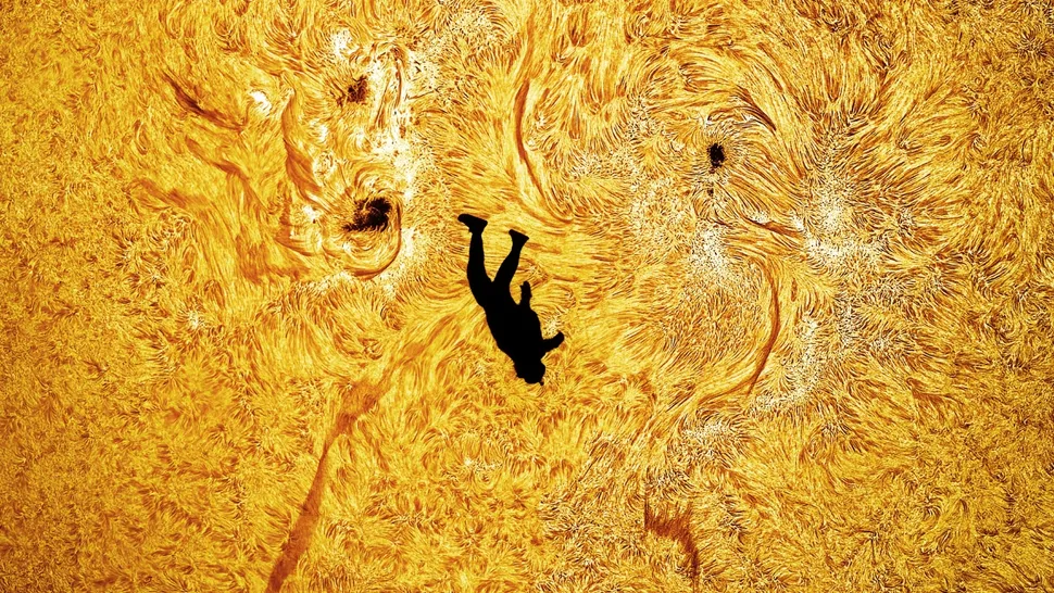 A silhouette of a man in front of the turbulent surface of the sun.