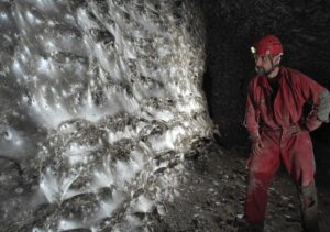 a man in a cave observing a massive spiderweb