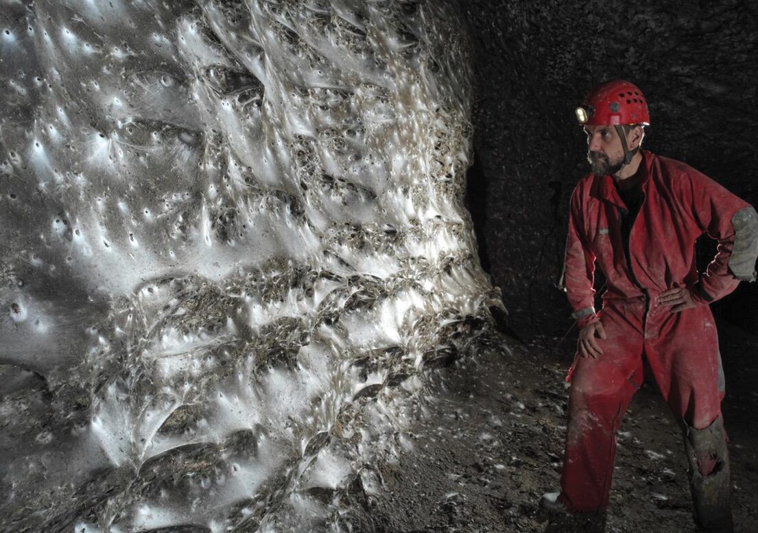 a man in a cave observing a massive spiderweb