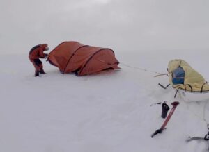 Colin O'Brady setting up his tent, with it secured to his sled for safety.
