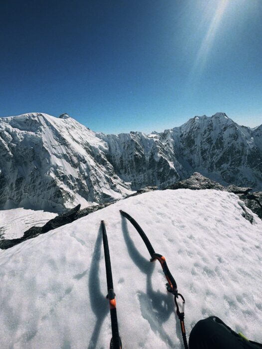 Two ice-axes on a snow ridge, mountains in background.
