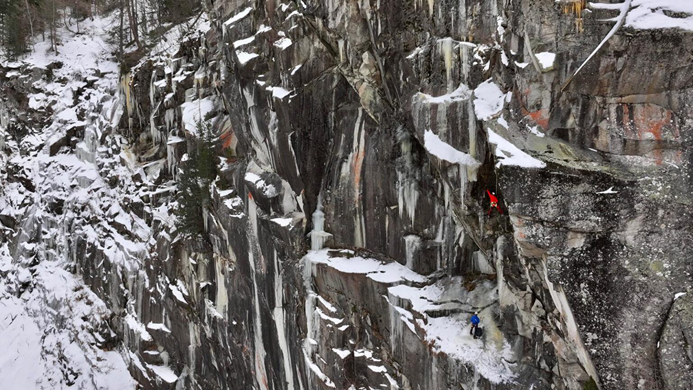Two climbers in bright colored jackets on a mixed granite face.