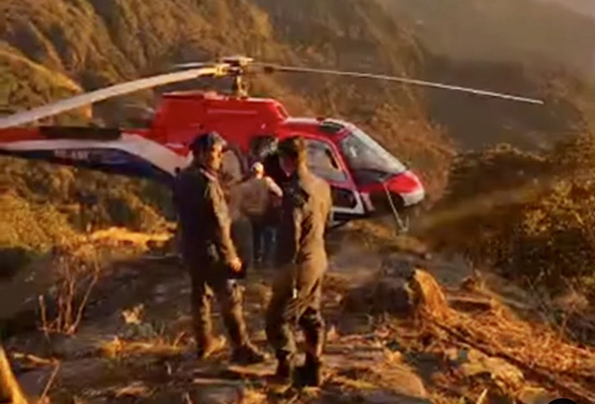 tw people stand beside helicopter in mountains