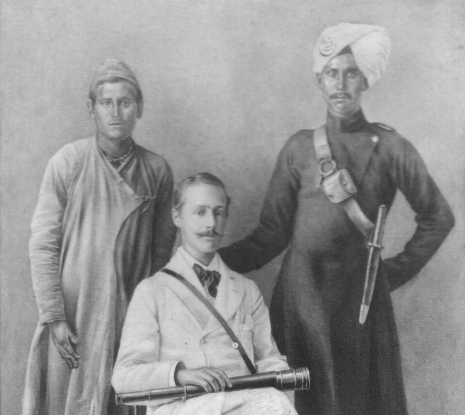 Three men, one seated and two standing