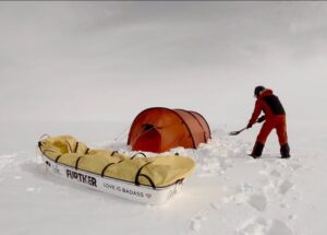 winter camper shoveling snow around his tent