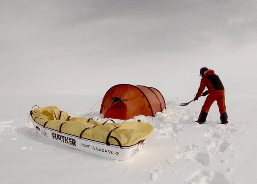 winter camper shoveling snow around his tent