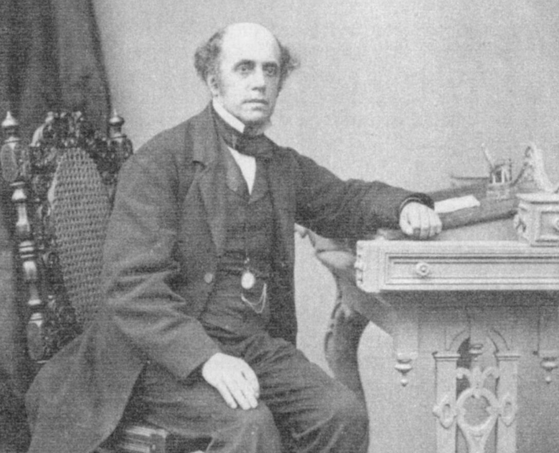 A man sitting at a desk wearing Victorian era clothing
