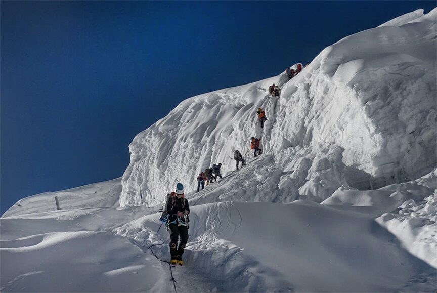 line of climbers going over a snowy obstacle