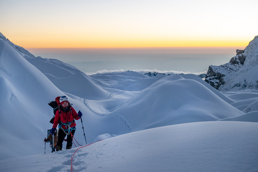 Climbers roped up on a glacier at dawn.