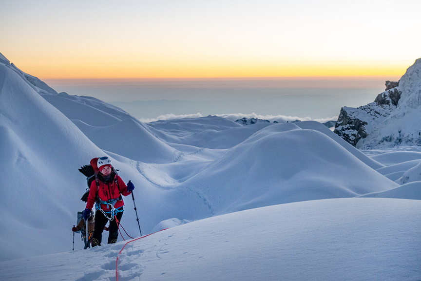 Climbers roped up on a glacier at dawn.