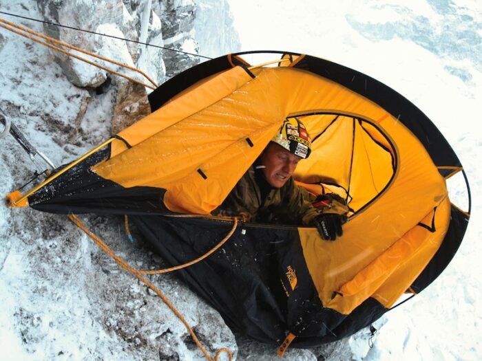 Urubko inside a tent dangerously tilted on a nearly vertical face.