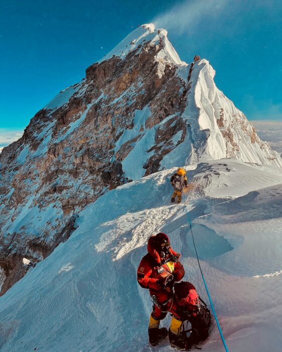 A line of climbers on the summit ridge of Everest in a windy morning.
