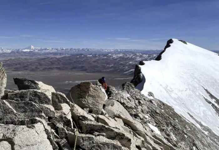 A snow covered summit from a rocky ridge.