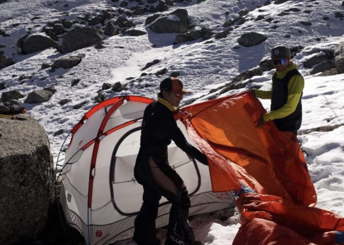 Two Nepalese climbers pitching a tent.