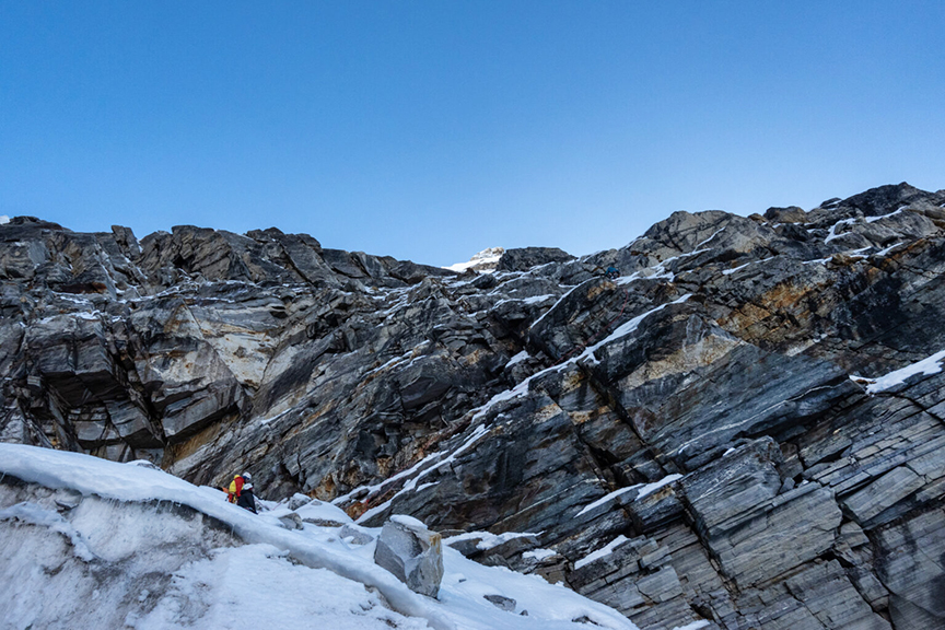 Climbers in front of a rocky wall.