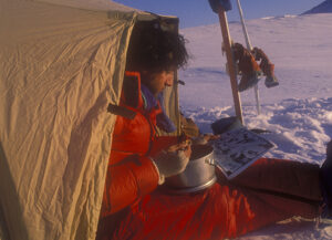 man sitting outside tent eating
