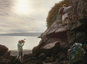 An old man filming a young man climb a cliff