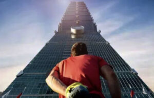 Alex Honnold at Taipei 101 with chalk bag gazing up.
