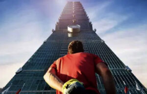 Alex Honnold at Taipei 101 with chalk bag gazing up.