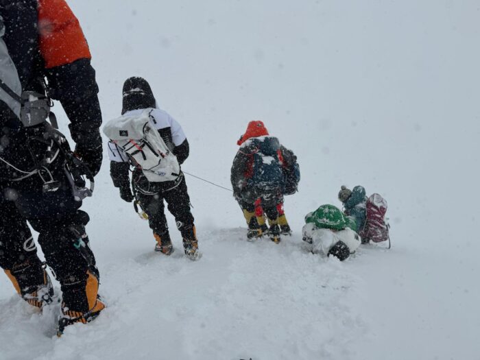 Climbers in a whiteout descending in line on the snow. 