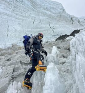 Sanu Sherpa in mountaineering outfit on an icefall with a big serac behind him.