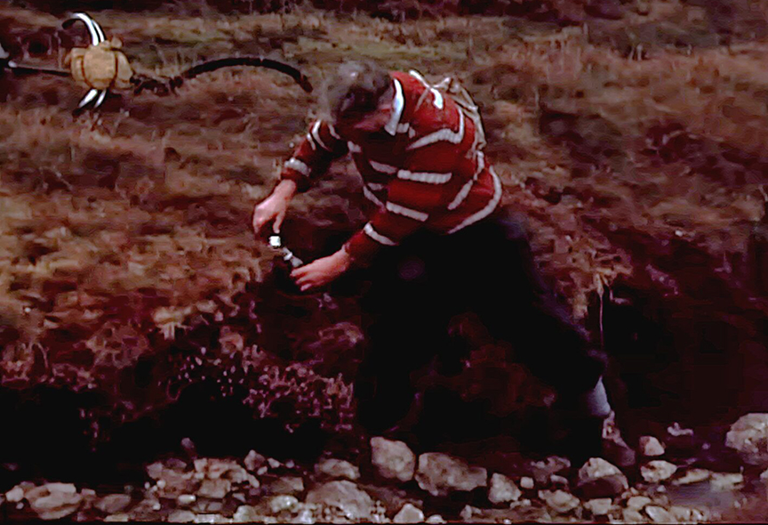 A man removes a bottle from a rock.