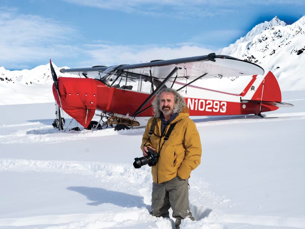 Chris Owens stands in front of a small red plane