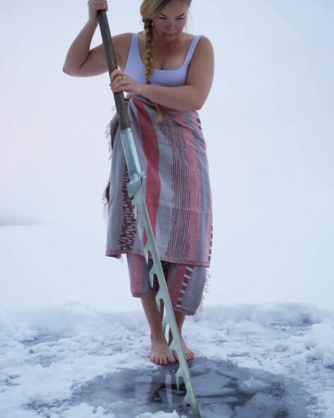 Elina Mäkinen cuts a hole in the ice