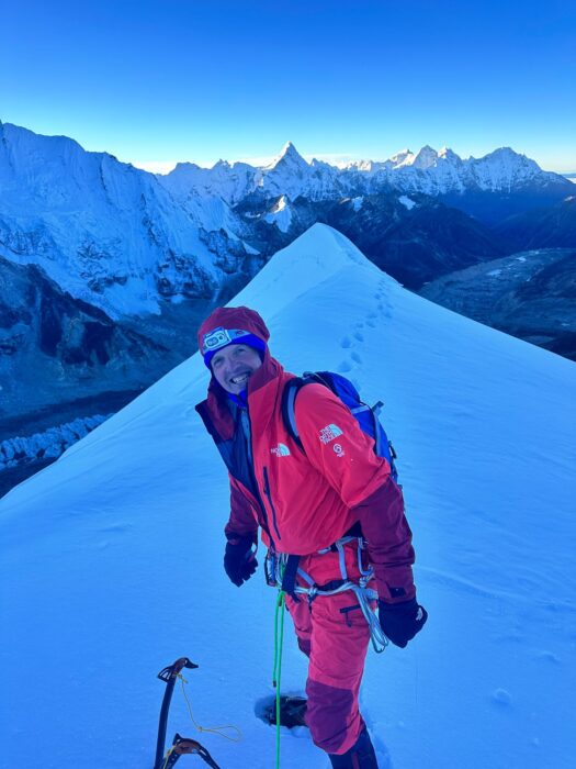 Simone Moro on a snowy summit in dim light. 