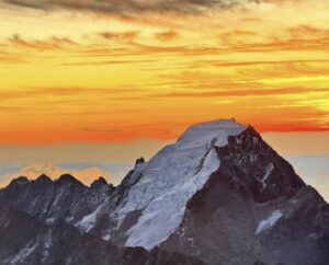 A peak under an orange-lit sky.