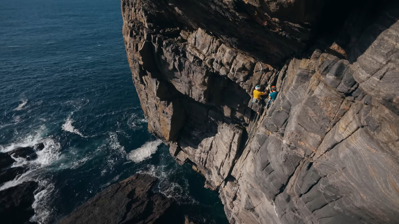 Two men on a rock face above the sea