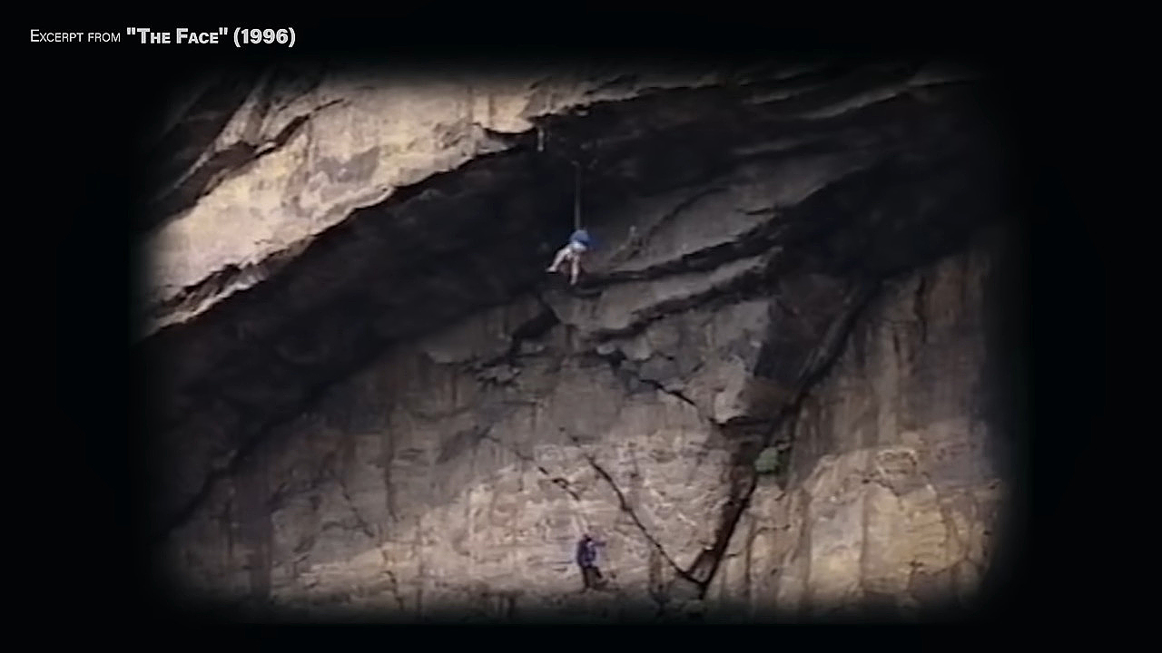Archival footage of a man climbing a sea cliff