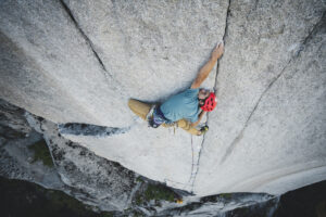 A climber up a blind crack on a smooth granite wall.
