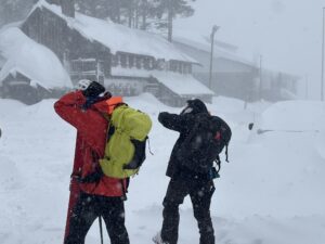 Skiers adjusting their helmets in the middl of a snowstorm.