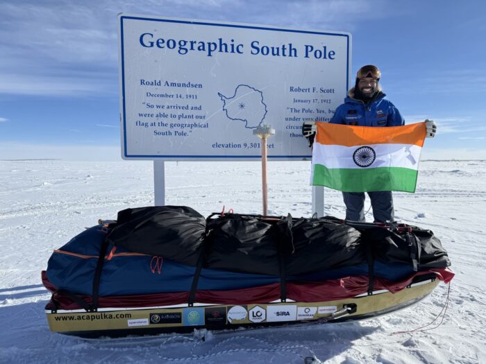 Satish Gogineni standing at the Geographic South Pole marker in Antarctica.