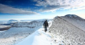 A hiker walks along the snowy ridge of Foinaven in Scotland
