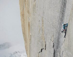 A climber on a smooth, vertical granite wall in Patagonia.