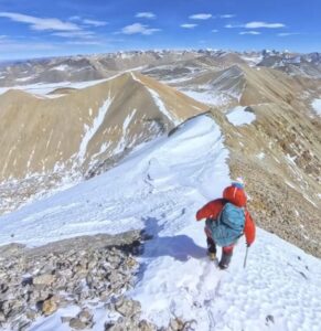 A climber on a scree and snow slope.