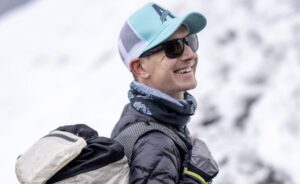 Close shot of Tyler Andrews with cap, sunglasses and a backpack.