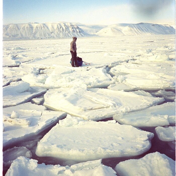 A man stands next to his sled on broken sea ice