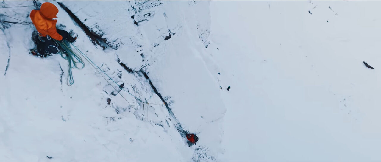 Two people climbing a snowy cliff