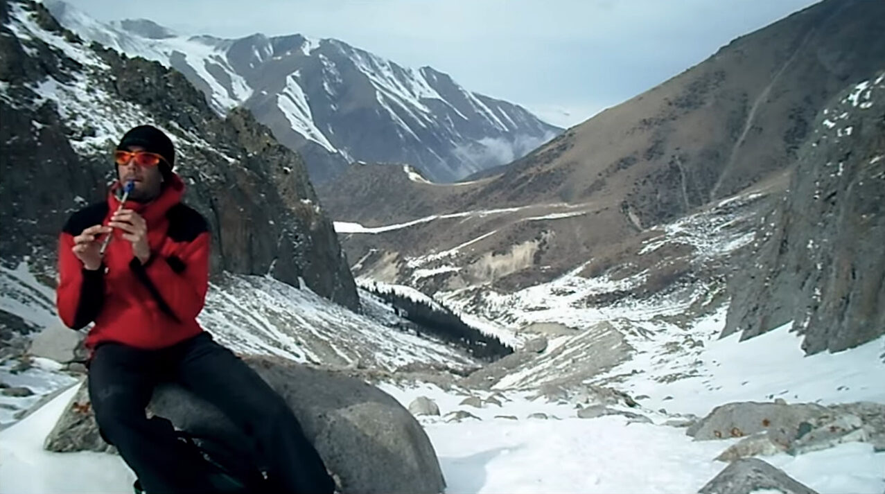 A man in the mountains playing a flute
