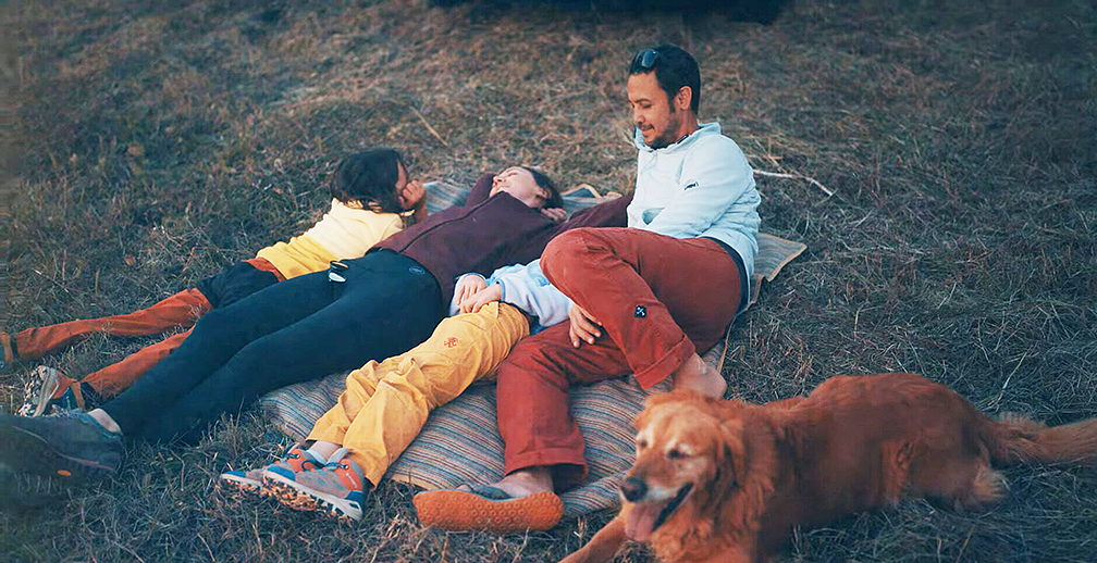 A family of four and a dog laying in the grass