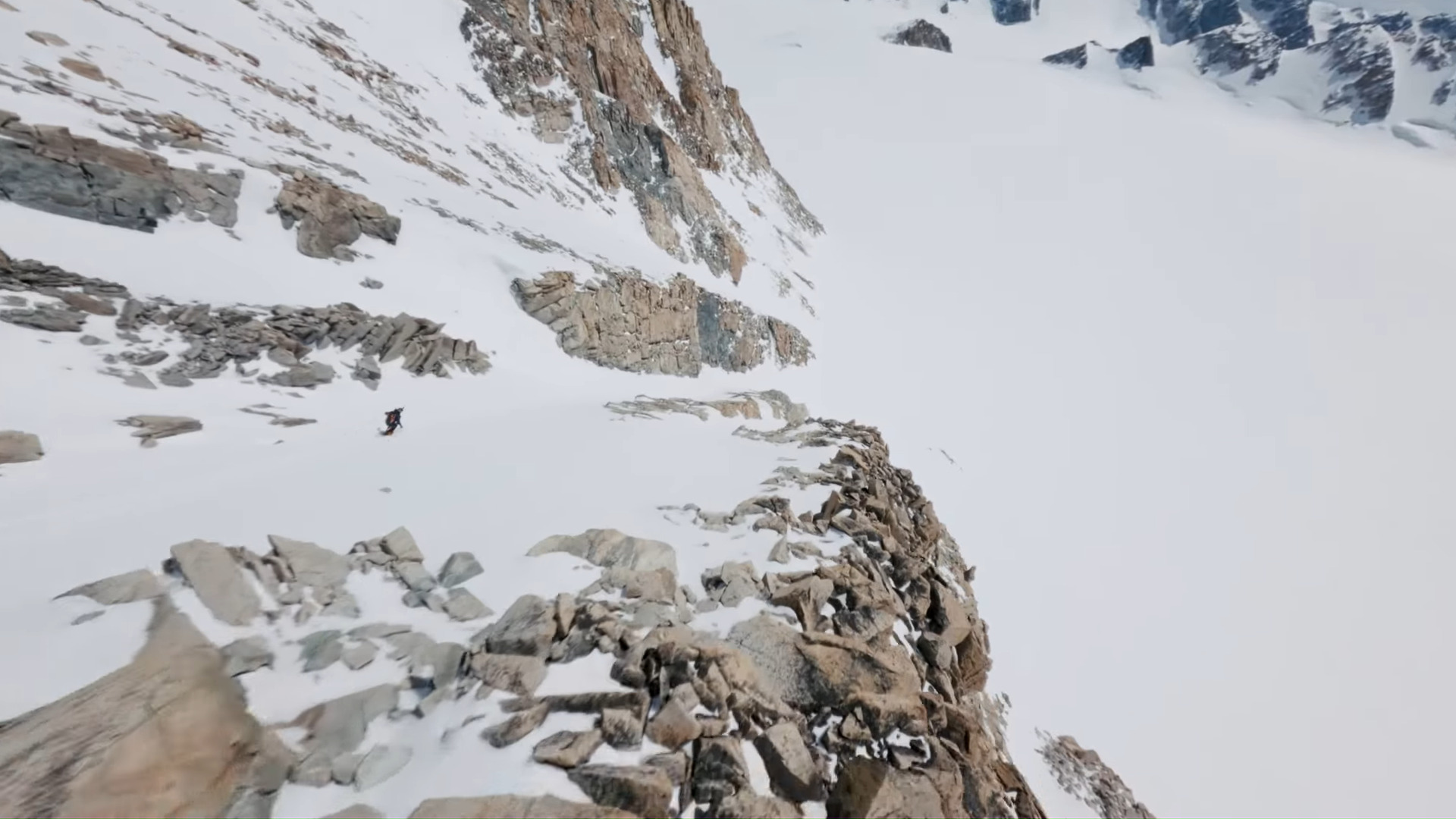 A skiier on a steep, rocky slope