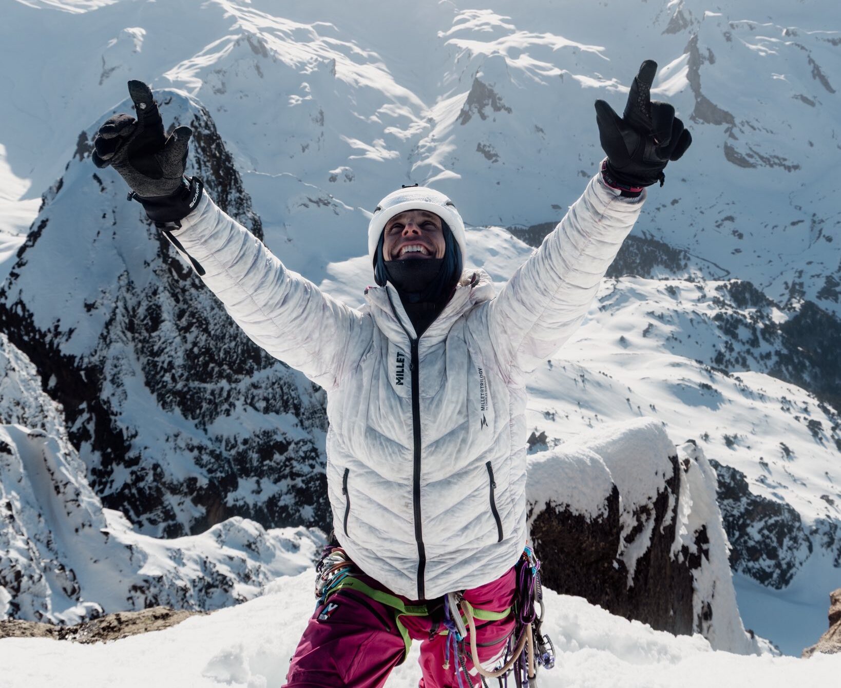 Climber Charles Dubouloz raises his arms in triumph on a snowy summit.